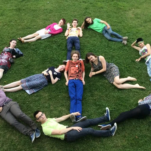 Участни:цы Движения изображают знак мира, лежа на газоне.